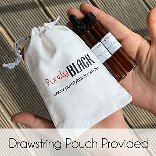 Hand holding a white drawstring pouch with essential oil bottles